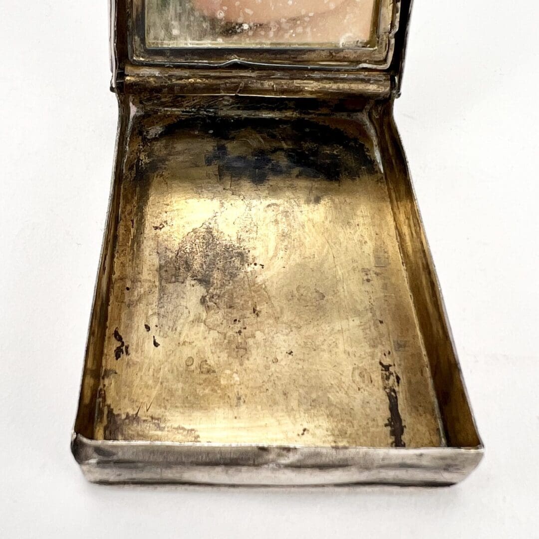 Open vintage metal compact with mirror.