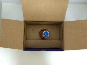 Bottle in open cardboard box, top view.