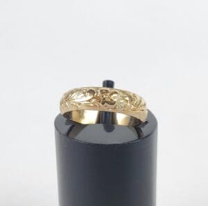Gold ring with floral engraving on stand.