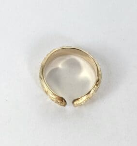 Gold open-ended ring on white background.