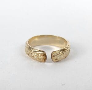 Gold open ring with engraved design.