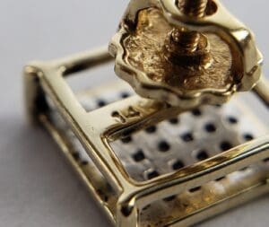 Gold earring with screw back detail.