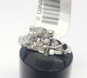 Diamond ring on black stand with tag.