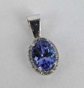 Silver pendant with blue gemstone and diamonds.