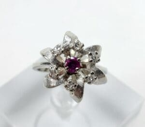 Silver floral ring with central purple gem.