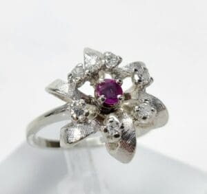 Silver ring with purple gemstone and diamonds.