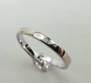 Silver ring with engraved hallmarks on band.