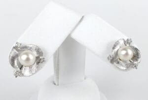 Silver pearl earrings on display stand.
