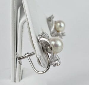 Pearl and silver screw-back earrings displayed.