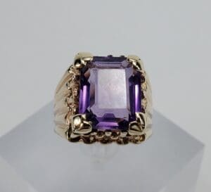 Gold ring with large purple gemstone.