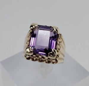 Gold ring with large purple gemstone.