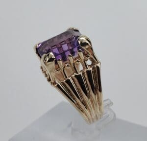 Gold ring with large purple gemstone.