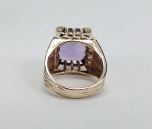 Gold ring with a purple gemstone setting.