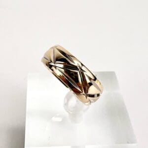 Gold geometric-patterned ring on display stand.