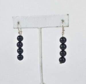 Black beaded dangle earrings on display stand.