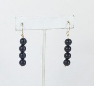 Black beaded earrings on a white stand.