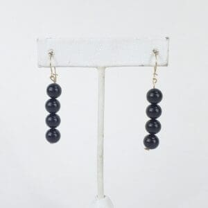 Black beaded earrings on display stand.