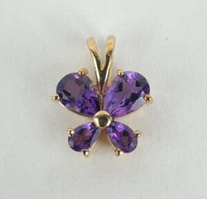 Gold pendant with purple gemstone butterfly.