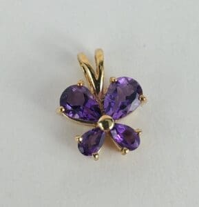Gold butterfly pendant with purple gemstones.