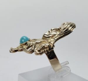 Gold ring with turquoise stone on display.