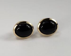 Gold earrings with black oval stones.
