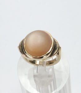 Gold ring with a round beige stone.