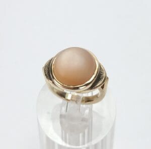 Gold ring with round gemstone on display.