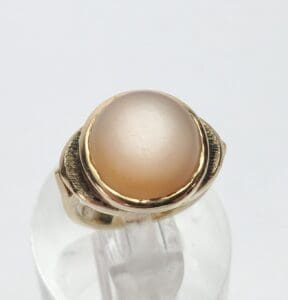 Gold ring with oval beige gemstone.