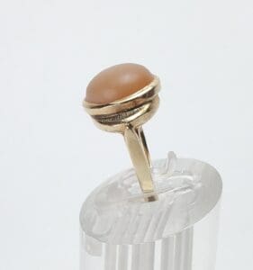 Gold ring with brown gemstone on stand.