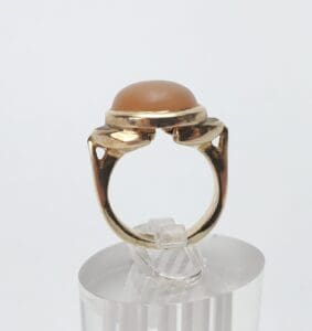 Gold ring with brown stone on stand.