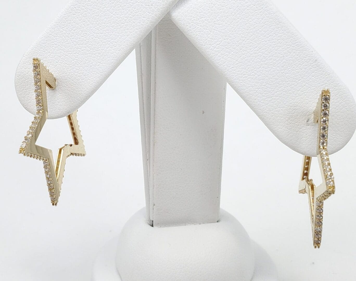 Gold star-shaped earrings on display stand.
