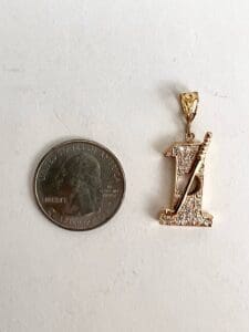 Gold pendant beside U.S. quarter coin.