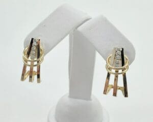 Gold and silver earrings on display stand.