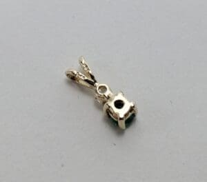 Gold pendant with gemstone on white background.