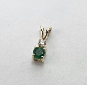 Gold pendant with emerald and diamond gemstones.