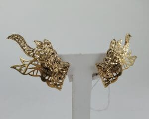 Gold dragon-shaped earrings on display stand.