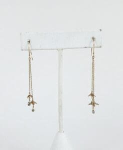 Gold dangling earrings on display stand.