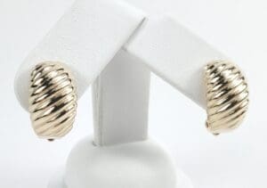 Gold-tone ribbed earrings on display stand.