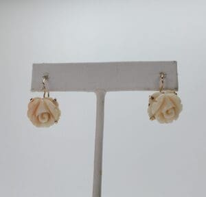 Rose-shaped earrings on display stand.