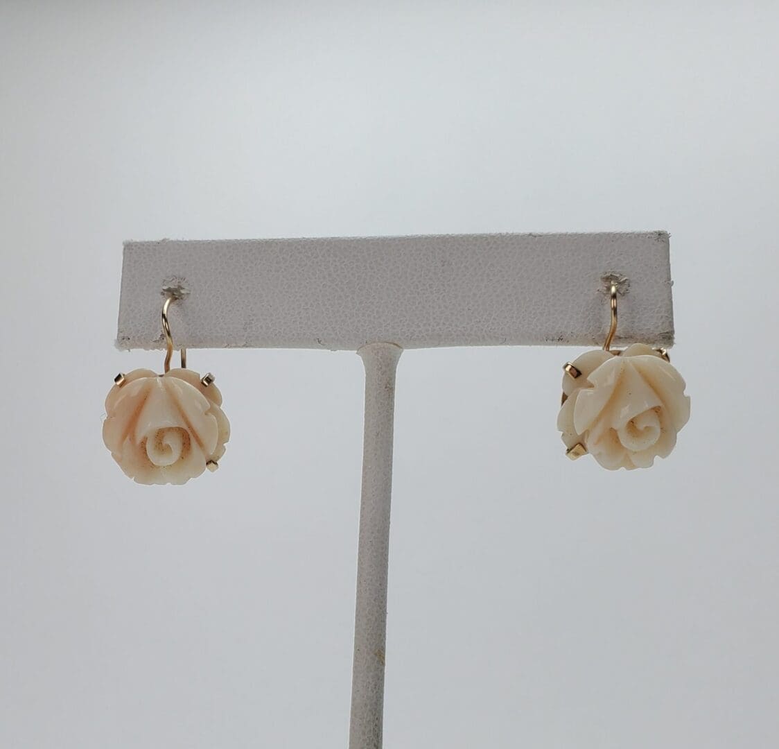 Rose-shaped earrings on display stand.