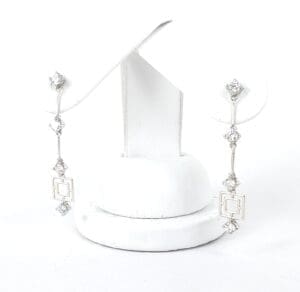 Silver earrings with geometric and diamond accents.