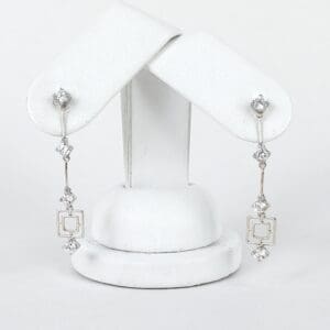 Silver earrings with geometric diamond accents.