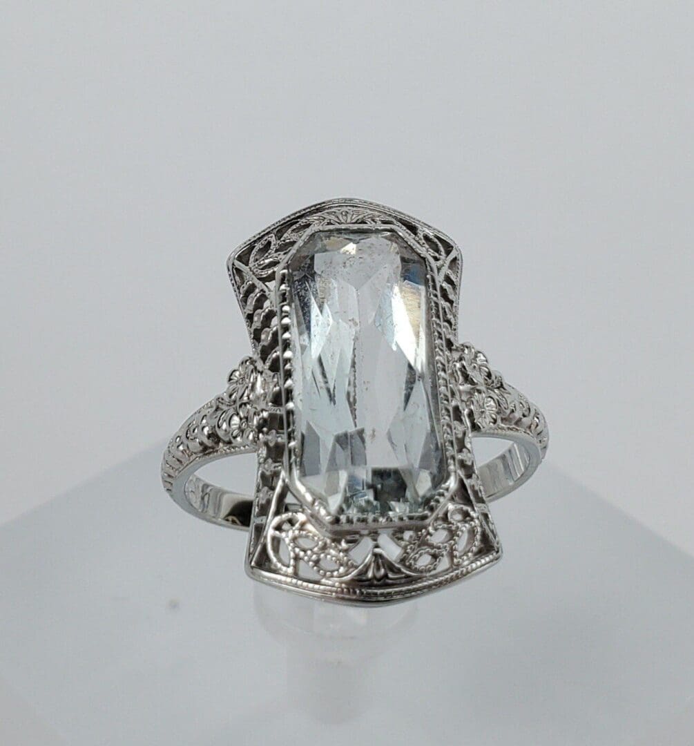 Ornate silver ring with clear gemstone.
