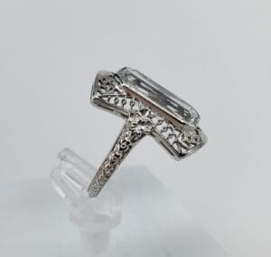 Ornate silver ring with large clear gemstone.