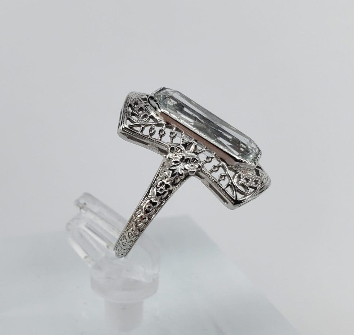 Ornate silver ring with large clear gemstone.