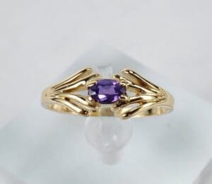 Gold ring with purple gemstone on display.