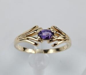 Gold ring with purple gemstone centerpiece.