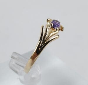 Gold ring with purple gemstone on display.
