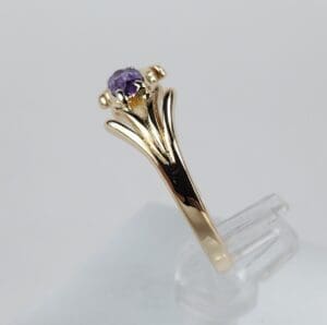 Gold ring with purple gemstone on display.
