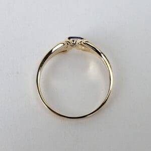 Gold ring with purple gemstone on top.
